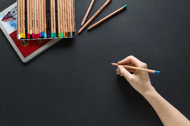 Drawing pencils and a hand holding a pencil 