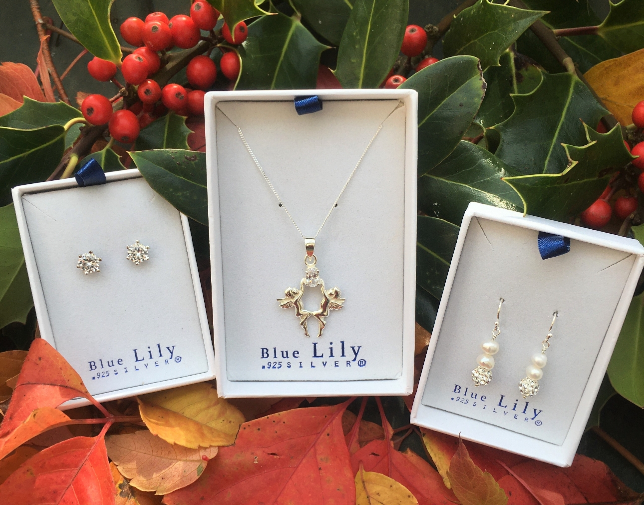 three white box with blue lettering containing three items of silver jewellery