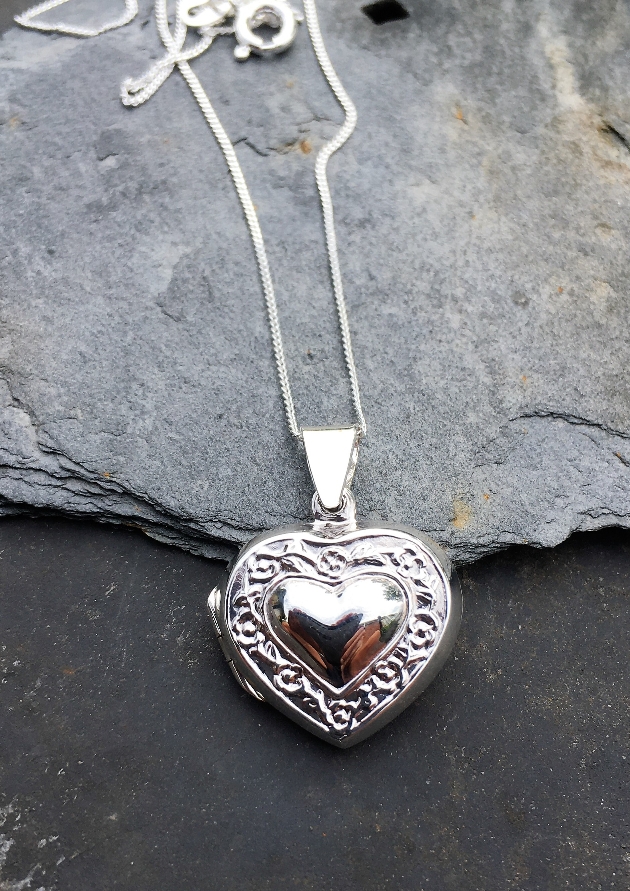 silver heart locket laying on a rock