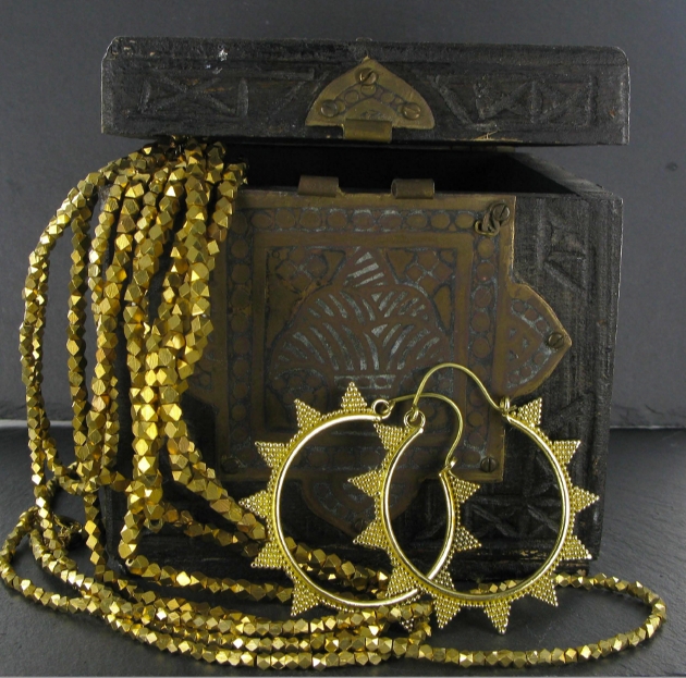gold jewellery in a black jewellery box aztec in style