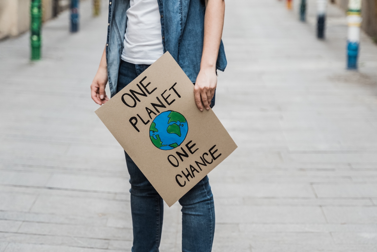 man holding a sign one planet one chance