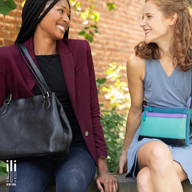 two models sitting on a bench holding bags