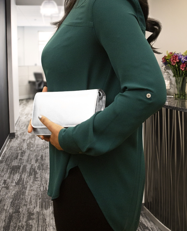 woman in green jumper holding a silver clutch bag 