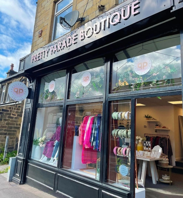 shop front black surround with pink company name banner and accessories can be seen through large window