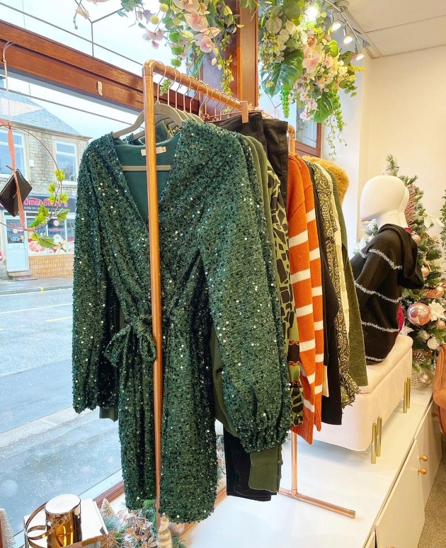 flowers covering shop window, clothes on rails, mannequins sat on footstool