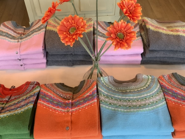 assortment of knitted coloured jumpers on a table