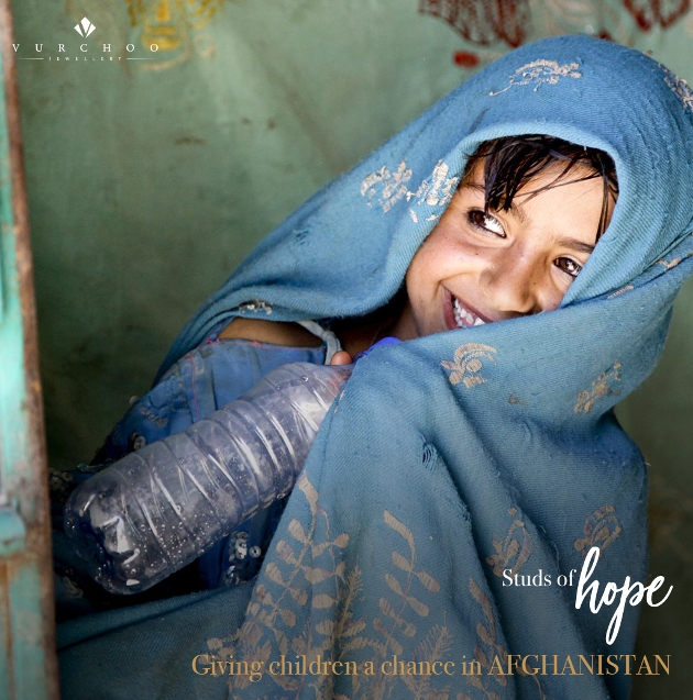 young Afghan girl in a blue head robe holding a bottle