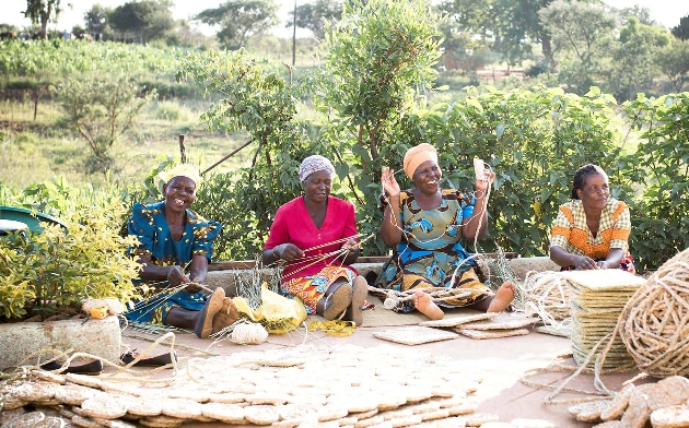 group of Zimbabwean women weaving in bright clothing
