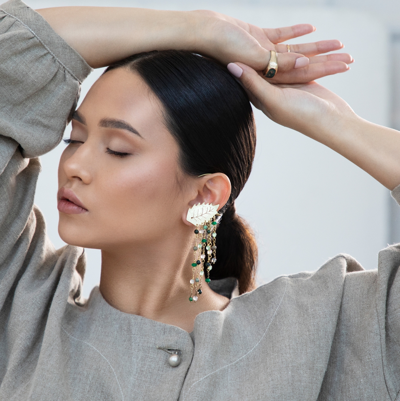 model with arms above her head with jewellery on