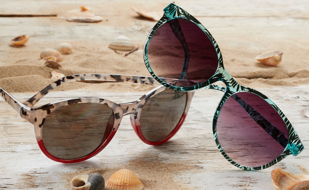 sunglasses on beach one in blue palm tree pattern one in leopard print and red