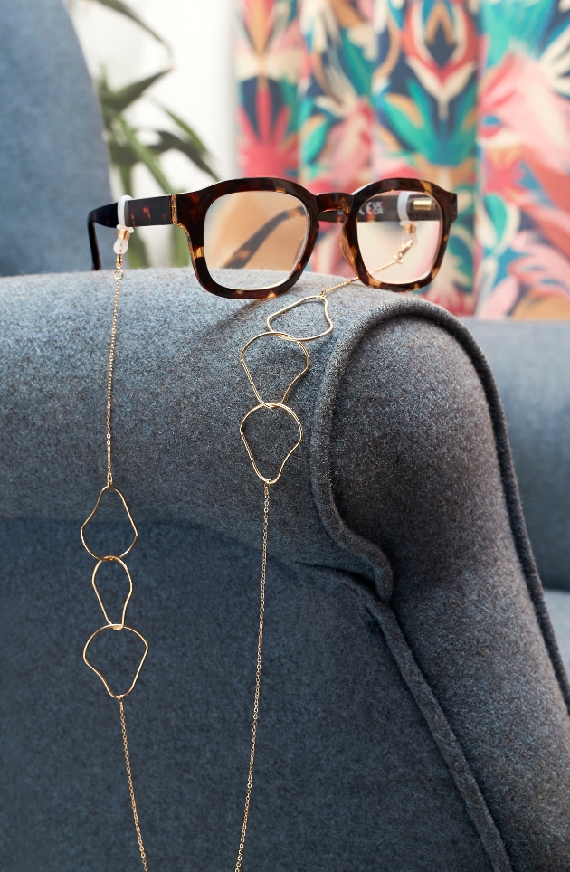 glasses on arm of chair with gold heart chain
