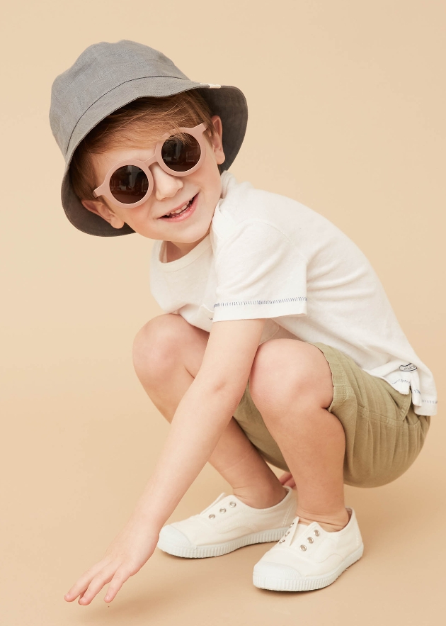 young boy in summer clothes with hat and glasses on