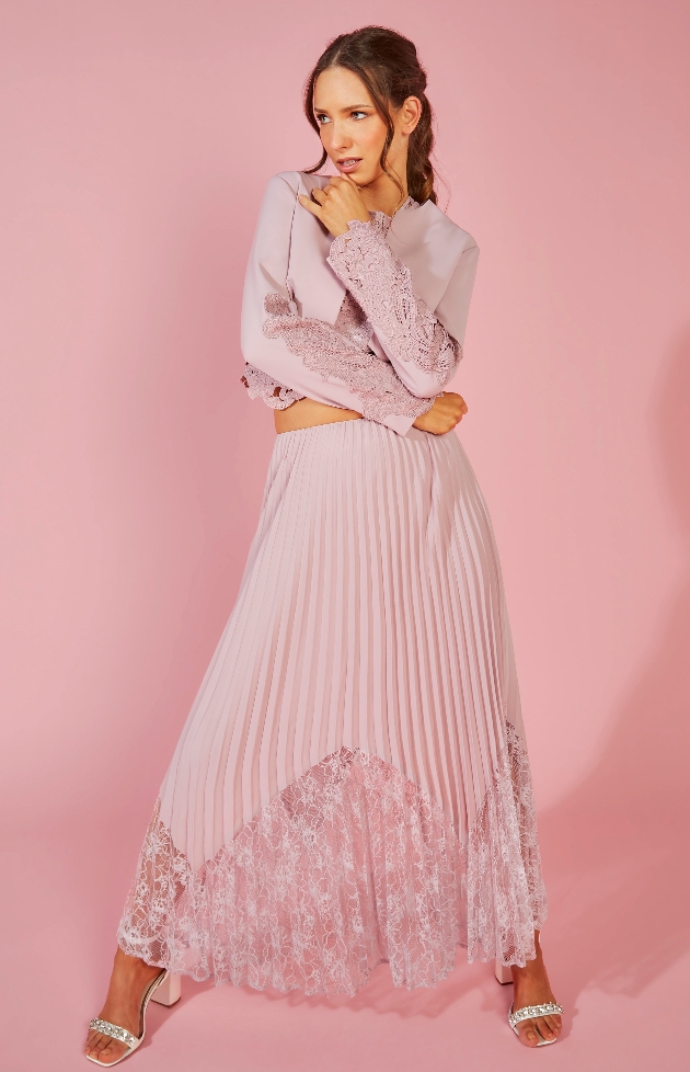 model in pink pleated skirt with lace trim, matching jacket