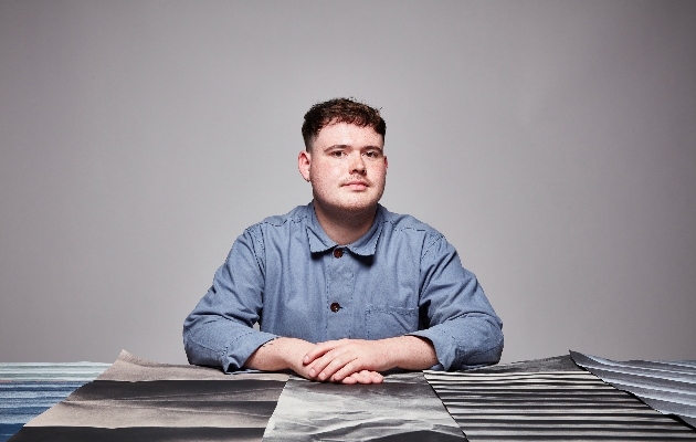 man in blue shirt sat at table with material in front of him 