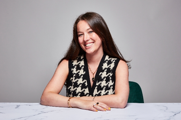 woman in black and white jumper with gold jewellery sat at table 