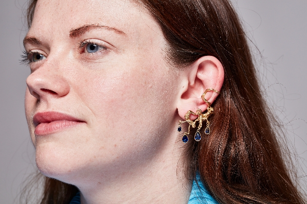 close up of blue an dgold earring on a woman's ear