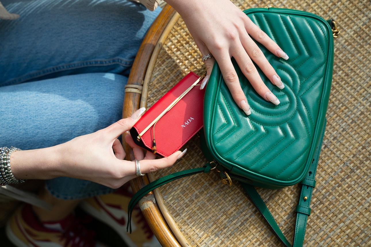 red sunglasses case being pulled out of a green handbag