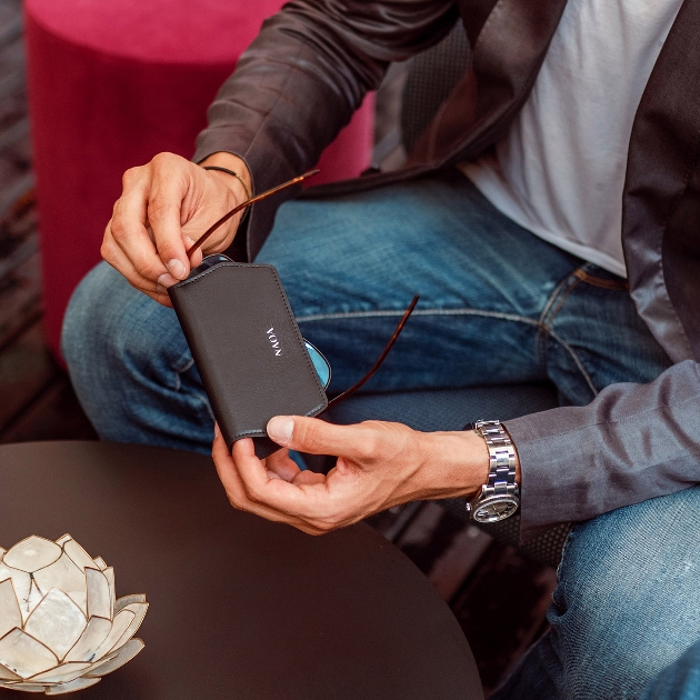 man in jeans and leather jacket holding black glasses case