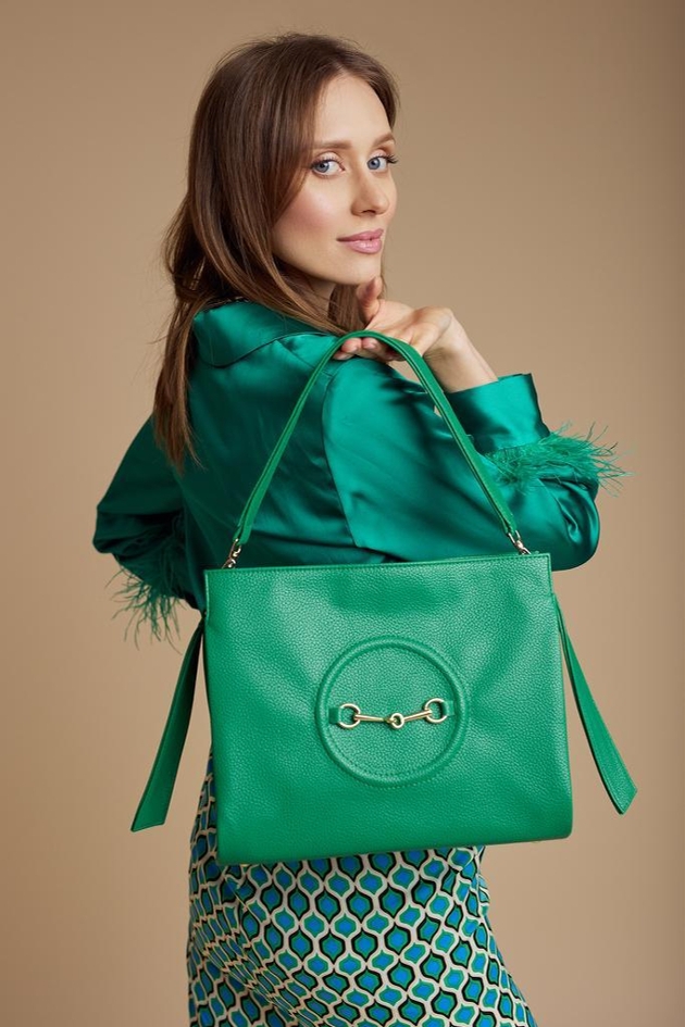 model with brunette hair holding a green bag