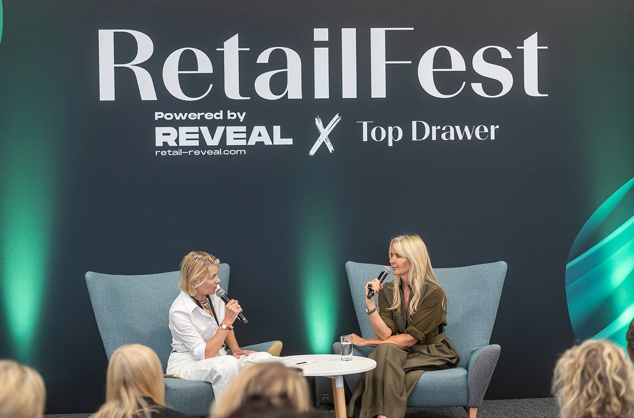 interviewer on stage with amanda wakley having chat while in green chairs 