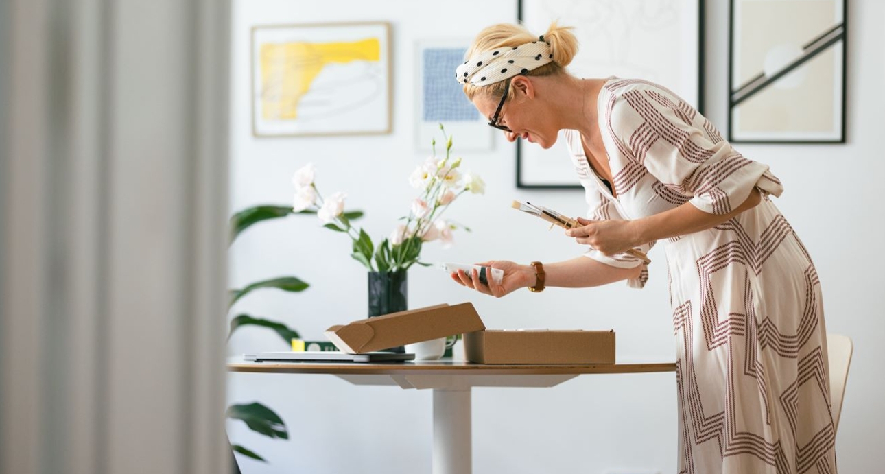 woman standing over table looking at gift box
