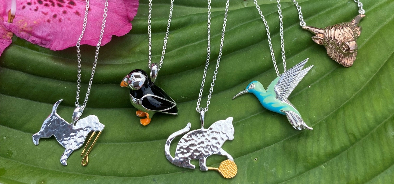 five necklaces displayed on a leaf, animal pendants 