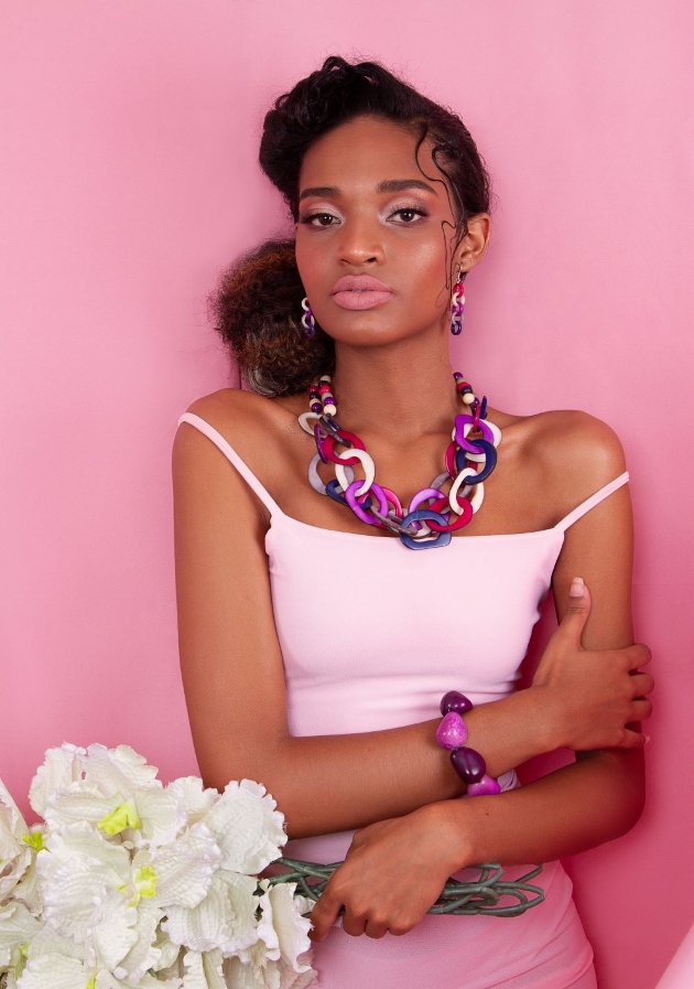 model in chunk pink toned jewellery earring and necklace sit with different bracelet