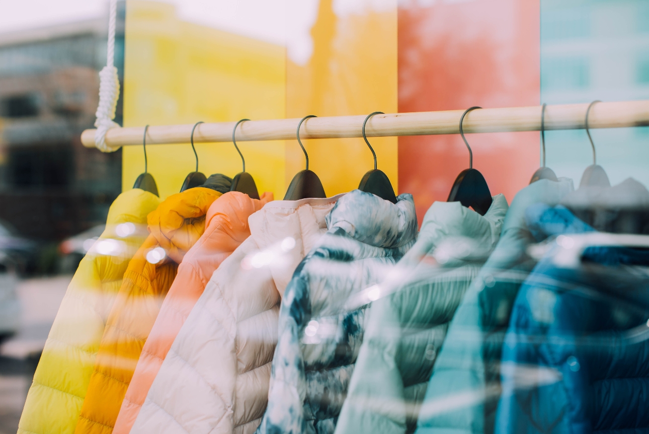 a row of colourful coats on a rack in a shop window